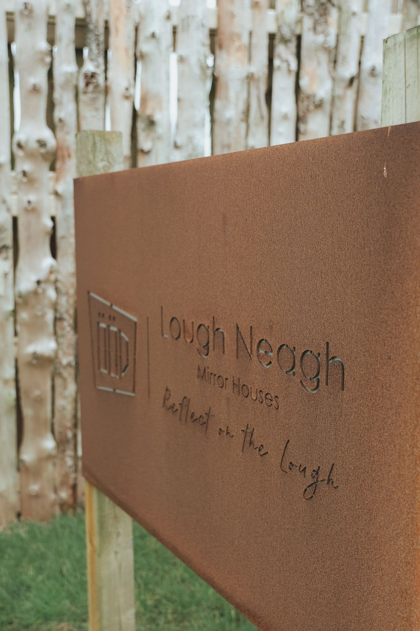 The corten steel Lough Neagh Mirror Houses sign at the entrance