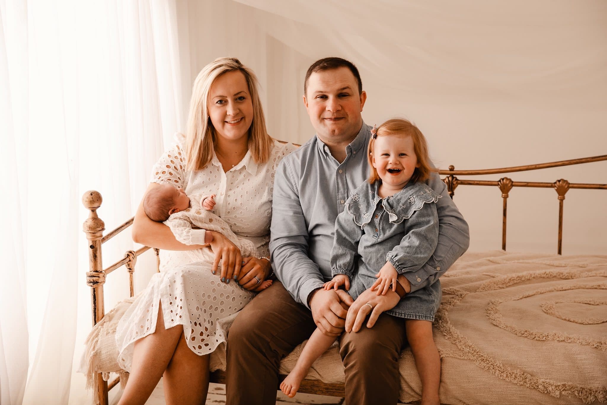 Andrew and Chloe Patterson sitting together, Chloe holding baby Freddie and Poppy on Andrew's knee