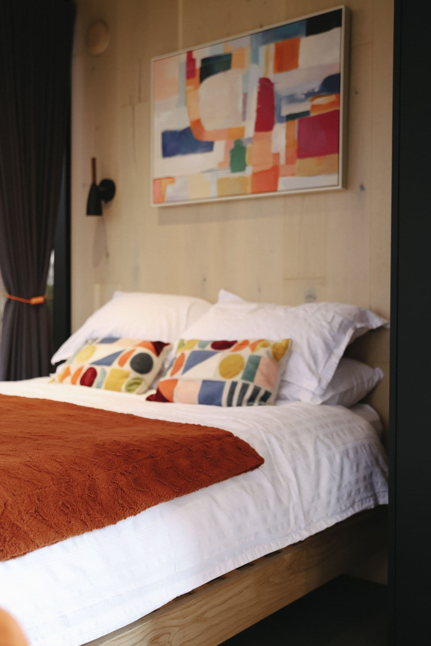 Inside Sunset — the bed with its rust throw and the artwork above the headboard